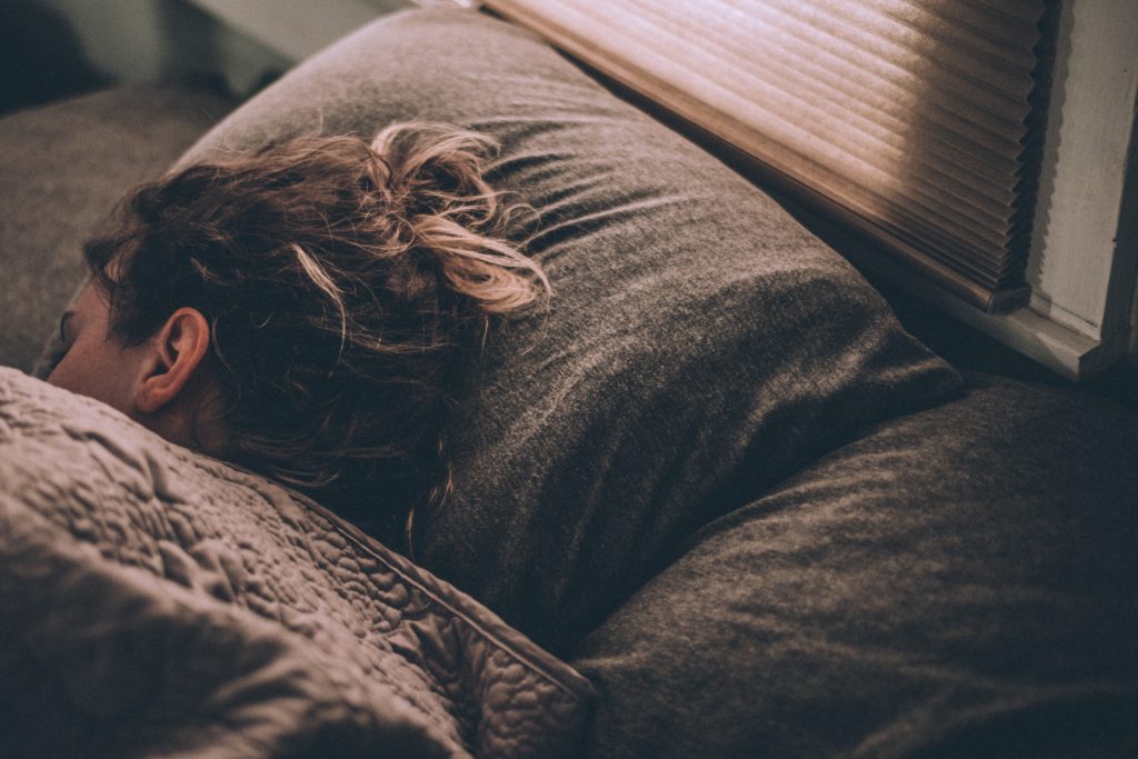 femme endormie dans un lit avec la tête sur les oreillers