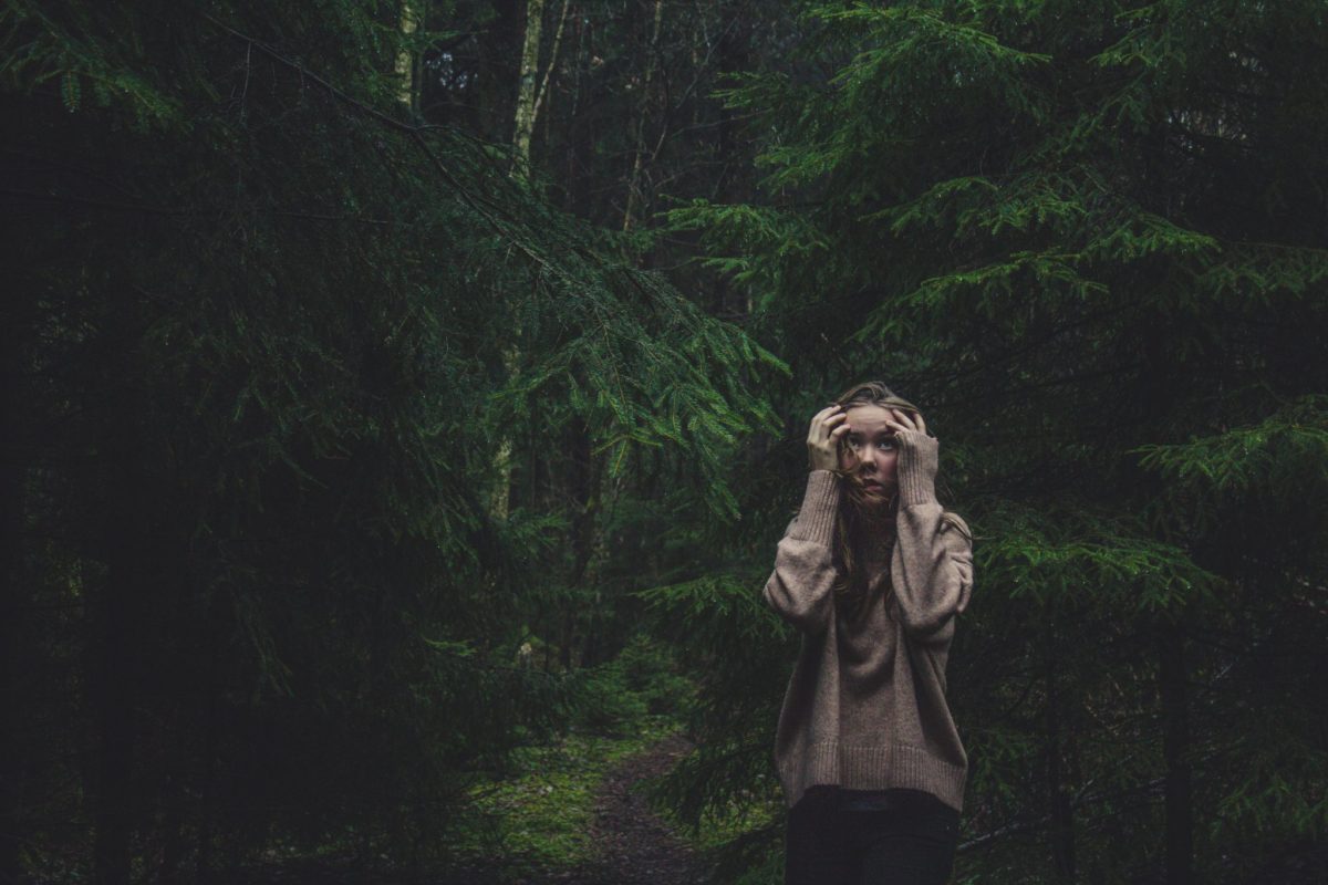 femme effrayée dans la forêt avec les mains sur la tête