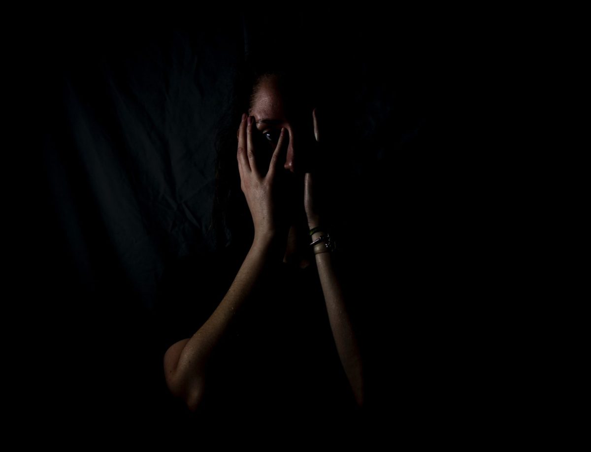 Femme dans le noir tenant ses mains sur sa tête